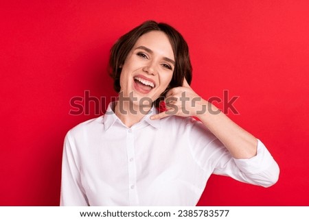 Photo of lovely happy nice young woman hold hands make call me sign smile isolated on red color background