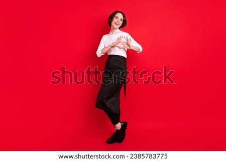 Full size photo of cheerful positive young woman wear uniform hostess show heart shape isolated on red color background