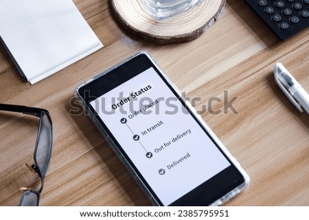Online purchase order status on the smartphone. Wooden desk background,  delivery tracking concept. Royalty-Free Stock Photo #2385795951