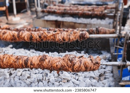 Easter in Greece, process of cooking traditional greek Easter dish - grilled Kokoretsi, a lamb or goat intestines and offal, grilling Kokoreç in the streets of Athens, Greece, roasted kokorec rolls Royalty-Free Stock Photo #2385806747