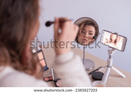 Caucasian woman leads an online make-up lesson for herself on her mobile phone