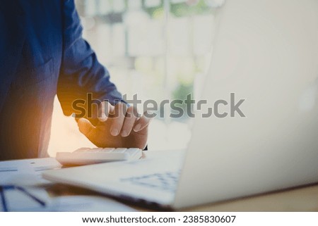 Young Asian businessman working with laptop, checking graphs, company budget reports, production control. Operational inspection cost plus price Close-up pictures