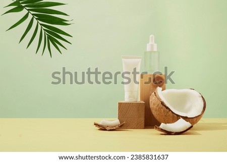 Pastel background with unlabeled cosmetic bottles placed on wooden podium. Fresh coconut and tropical palm leaves. Mockup for vegan cosmetics advertisement. Royalty-Free Stock Photo #2385831637