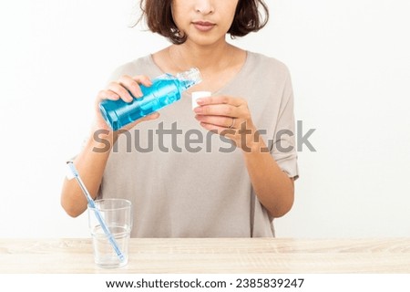 A Japanese woman uses mouthwash. Royalty-Free Stock Photo #2385839247