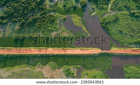 Aerial view of Transpantaneira dirt road crossing a river by a wooden bridge, lush vegetation around