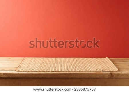 Empty wooden table with bamboo place mat  over red background. Chinese New Year mock up for design and product display.