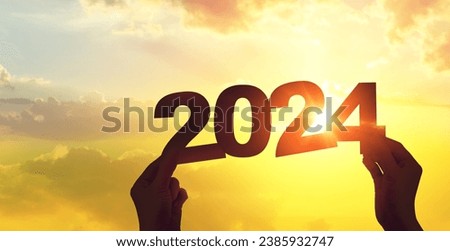 Silhouette hand holding 2024 year on sunset sky. Happy new year to plan and starting new life concept.