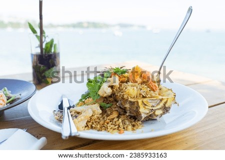 Seafood fried rice in pineapple, appetizing in a cafe next to the sea, Sue Flamingo, Ao Yon Beach, Phuket Thailand Royalty-Free Stock Photo #2385933163