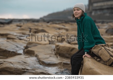 Beautiful travel woman sitting on the rock and looking to the sea