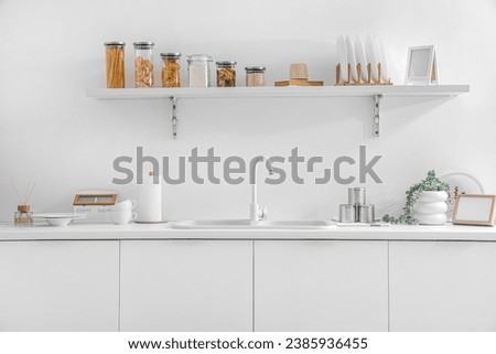 White counters with sink and utensils in interior of modern kitchen Royalty-Free Stock Photo #2385936455