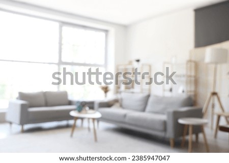 Blurred view of light living room with grey sofas and coffee table