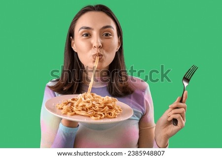 Young woman eating tasty pasta on green background, closeup Royalty-Free Stock Photo #2385948807