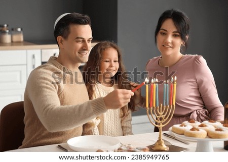 Happy family lighting candles for Hanukkah in kitchen Royalty-Free Stock Photo #2385949765