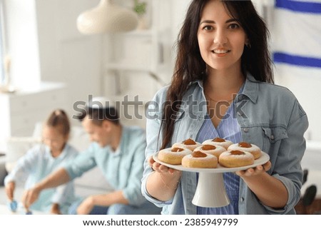 Young woman with donuts celebrating Hanukkah at home