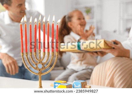 Happy family celebrating Hanukkah with menorah at home, closeup Royalty-Free Stock Photo #2385949827