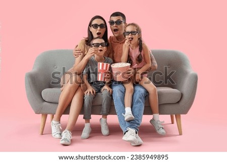 Shocked family with popcorn watching movie on sofa against pink background
