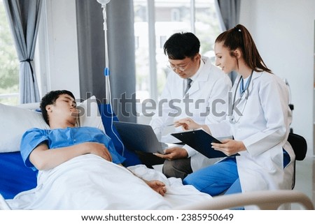 Two doctors talking to a patient lying in his bed  with receiving saline solution in modern hospital 
