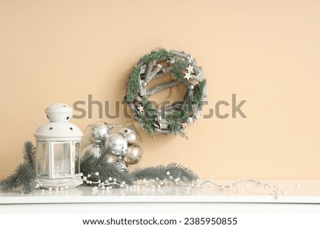 Christmas lantern with fir branches and balls on shelf in room