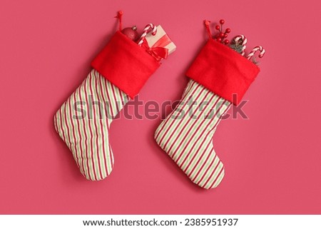Christmas socks with beautiful decorations and gift box hanging on pink background