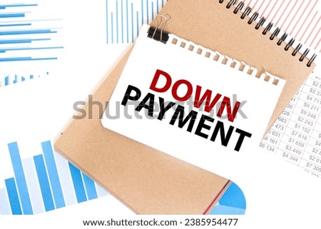 Text DOWN PAYMENT on white paper sheet and brown paper notepad on the table with diagram. Business concept