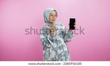 Portrait of hijab girl using smartphone in trendy style, isolated over pink background