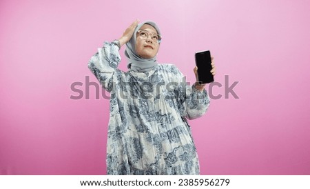 Portrait of hijab girl using smartphone in trendy style, isolated over pink background