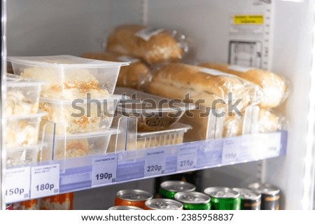 Close-up view of various prepared food lying on fridge shelf in micro market (small unattended vending store). Prepared food theme. Russian text translation: Salad Mimosa and Wok with chicken. Royalty-Free Stock Photo #2385958837