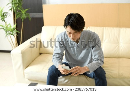 Asian man in casual clothes looking at his smartphone with a serious expression
 Royalty-Free Stock Photo #2385967013