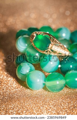 Fashion golden ring with green agate and beaded bracelet, close up background.