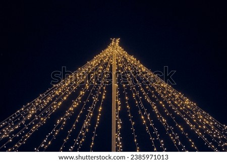 Yellow lights garlands outdoor hanging wires from pillar at night blue sky background, magic holiday atmosphere. Festive Christmas garlands with luminous yellow light, beautiful outdoor decoration