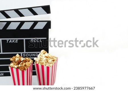Clapperboard or movie slate black color with popcorn on white background. Cinema industry, video production and film concept.