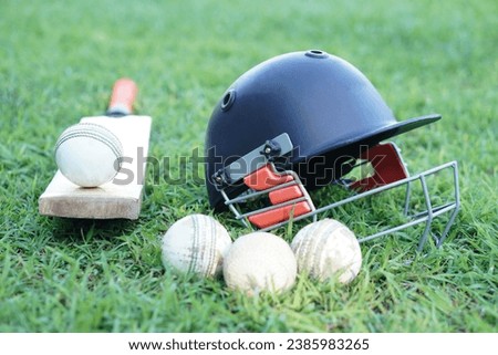 Cricket kits, helmet, cricket balls and bat on grass field. Concept, sport equipment. Well known competitive sport. Cricket is a bat-and-ball game played between two teams of eleven players on a field
