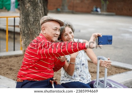 Senior Chinese tourist with his friend European poses happy and take a photo selfie on blurred of city background. Senior tourist concept