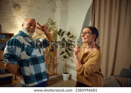 Adorable mature couple dancing of happiness, joyful while listening music and relax at home. Keep moving. Concept of love, retirement life, active lifestyle, fun, pensioners, cozy, winter holidays.