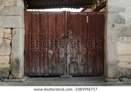 Front view of antique large double door with brown wood texture and rusty metallic vintage handle and bolts from a barn y a village in Spain.  Concept of architecture grunge vintage damaged doors