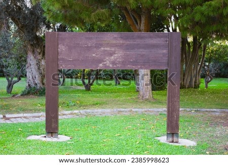 Wooden signboard or nameplate in a park on grass surface. Vintage look empty wooden board. Blank board in outdoor with text space.