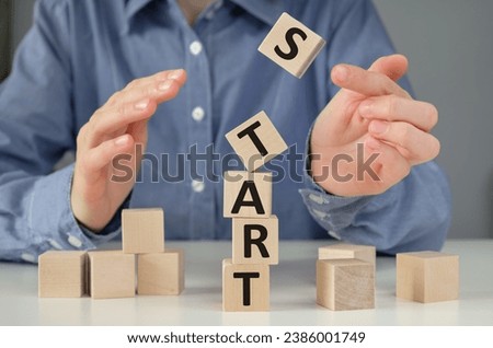 word start on wooden cubes with blurred woman hand pressing the start button for make a new start or restart in life, business, education or career concept