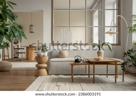 Open space interior with modular sofa, wooden coffee table, big window, beige rug, round pillow, stylish table, lamp, plants, vase with leaves and personal accessories. Home decor. Template. Royalty-Free Stock Photo #2386003191