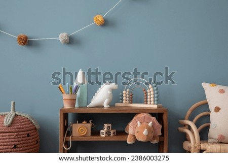 Interior design of warm kids room interior with wooden sideboard, plush toys, pillow, pink basket, colorful garland, wooden camera, abacus and personal accessories. Home decor. Template.