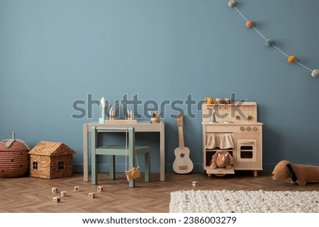 Cozy composition of living room interior with gray desk, green chair, guitar, kitchen for kids, colorful garland, plush toys, wooden block toys and personal accessories. Home decor. Template.