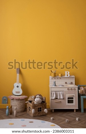 Minimalist composition of kids room interior with yellow wall, children kitchen, guitar, stylish bench, plush monkey, round rug, wooden block and personal accessories. Home decor. Template.