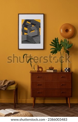 Interior design of sunny living room interior with mock up poster frame, stylish kilim rug, wooden sideboard, yellow wall, braided pouf, vase with leaves and personal accessories. Home decor. Template Royalty-Free Stock Photo #2386003483