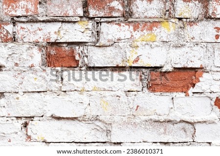 Old brick wall with white cracked paint. Rough brick wall texture. Abstract brick wall background for design. Close up.