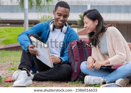 Two friends on campus sitting reviewing notes for the outdoor exam.