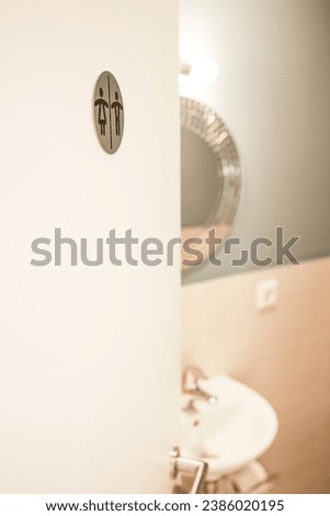 A half-open door to a unisex toilet.