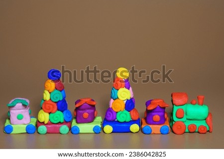A toy Christmas train made of plasticine with gifts and Christmas trees. Brown background. New Year decorations.
