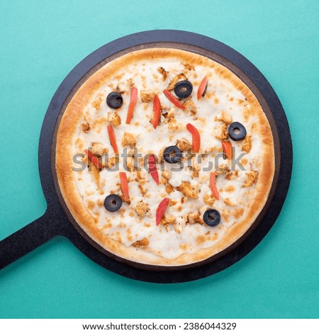 olives and tomatoes chicken cheese pizza with wooden pan on green background