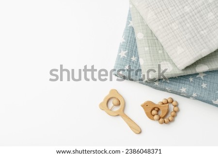 Muslin swaddle blanket with wooden toys on white background Royalty-Free Stock Photo #2386048371