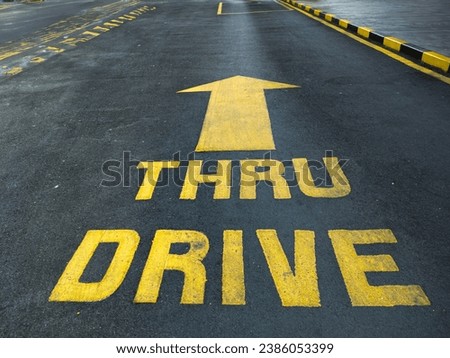 Asphalt road with yellow drive thru signage