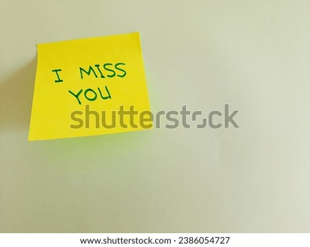 Message written on a yellow sticky note, 'I miss you', on blank sheet of white paper with copy space